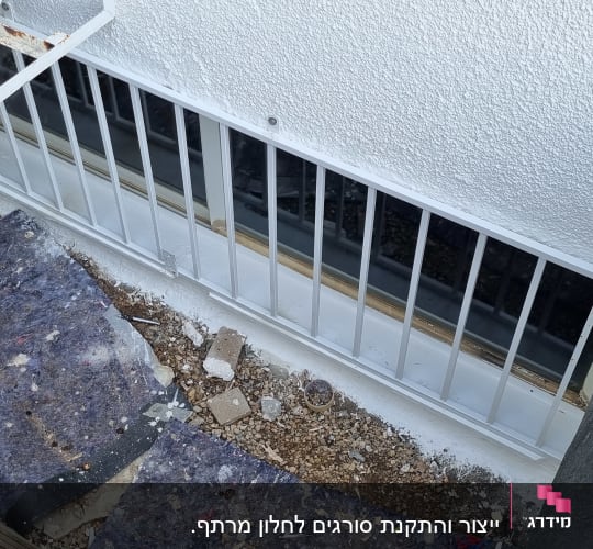 סורגי מתכת לבנים מותקנים על חלון קיר חיצוני